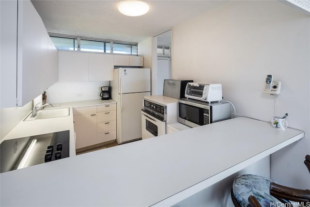 kitchen featuring white appliances, a toaster, light countertops, and a sink