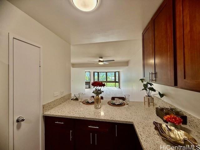 kitchen featuring a peninsula, light stone counters, and a ceiling fan