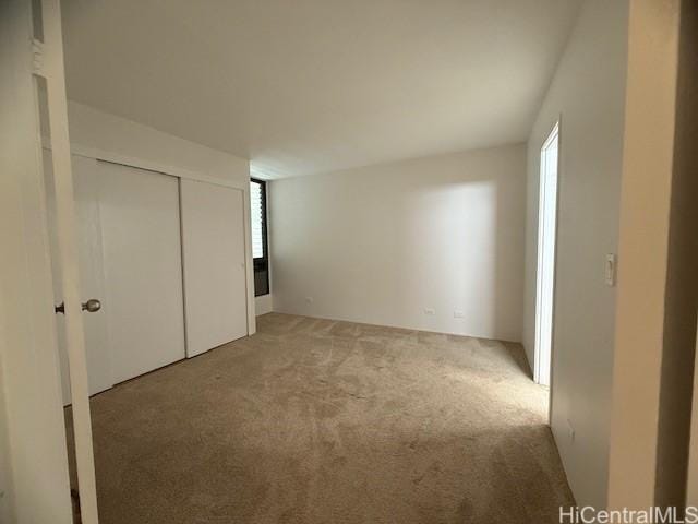 unfurnished bedroom featuring a closet and light colored carpet