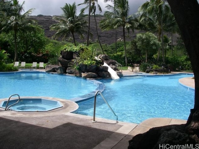 community pool featuring a water slide and a hot tub