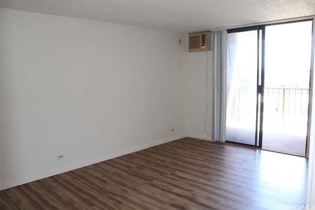 spare room featuring a wall of windows, dark wood-type flooring, a textured ceiling, and baseboards