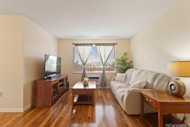 living room featuring a textured ceiling, baseboards, and wood finished floors