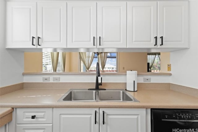 kitchen featuring dishwasher, light countertops, a sink, and white cabinetry