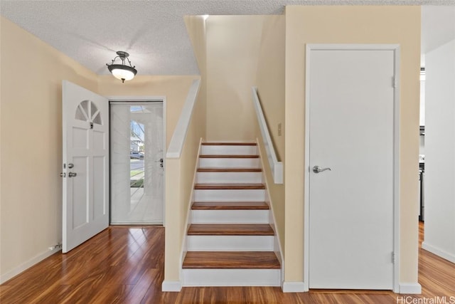 foyer featuring stairs, a textured ceiling, and wood finished floors