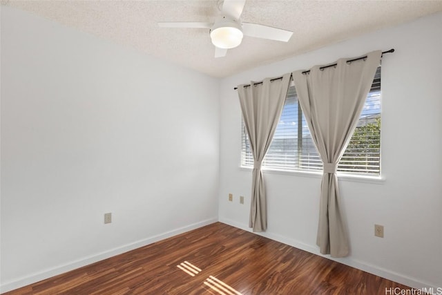 empty room featuring a textured ceiling, baseboards, and dark wood-style flooring