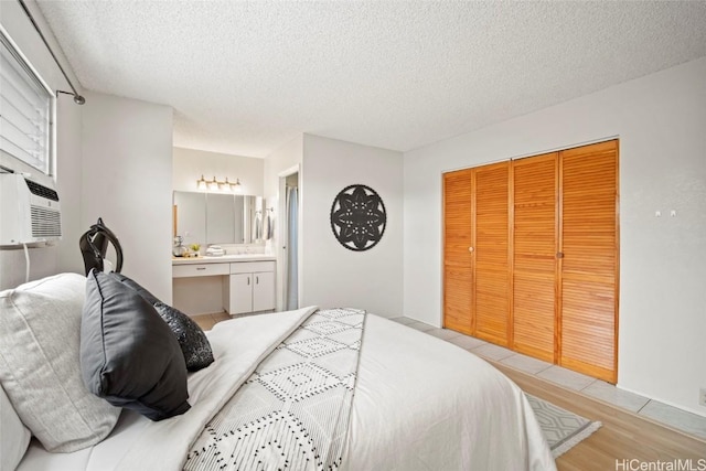 bedroom featuring a textured ceiling, light wood-style floors, a closet, and connected bathroom