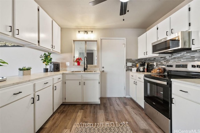 kitchen featuring light countertops, appliances with stainless steel finishes, a sink, and tasteful backsplash