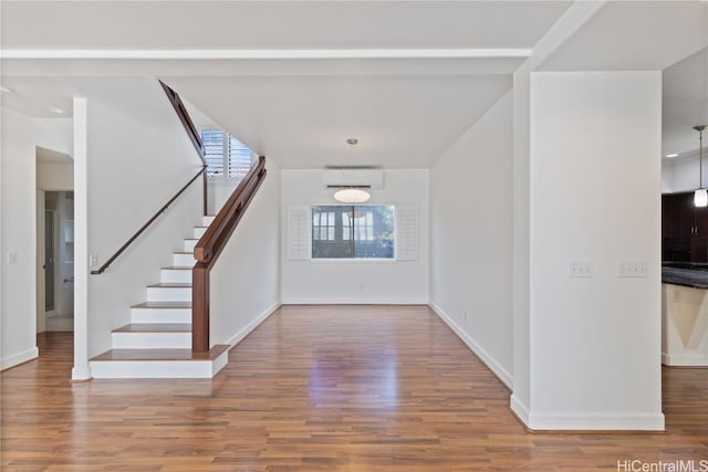 entrance foyer with stairway, a wall mounted AC, and wood finished floors