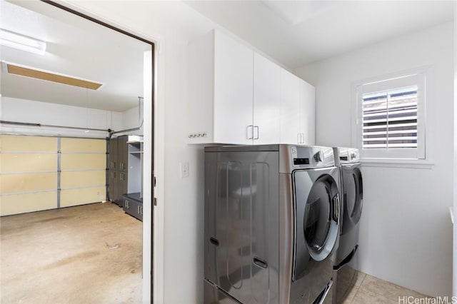 clothes washing area with a garage, cabinet space, and washer and dryer
