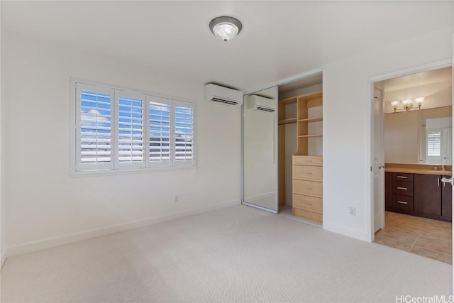 unfurnished bedroom with a closet, baseboards, an AC wall unit, and light colored carpet