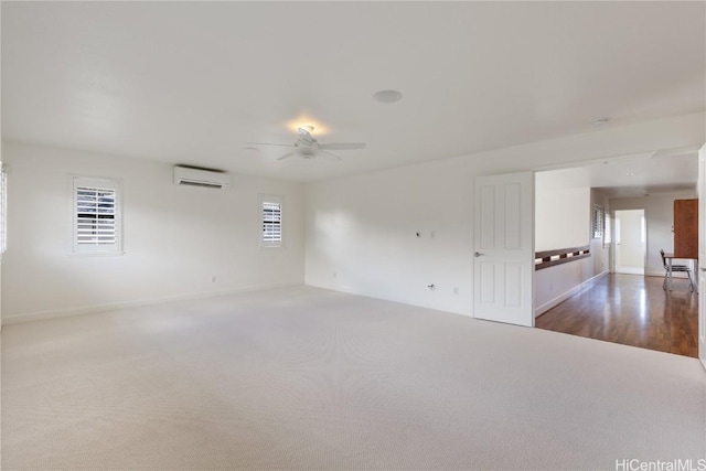 carpeted spare room featuring ceiling fan, baseboards, and a wall mounted AC
