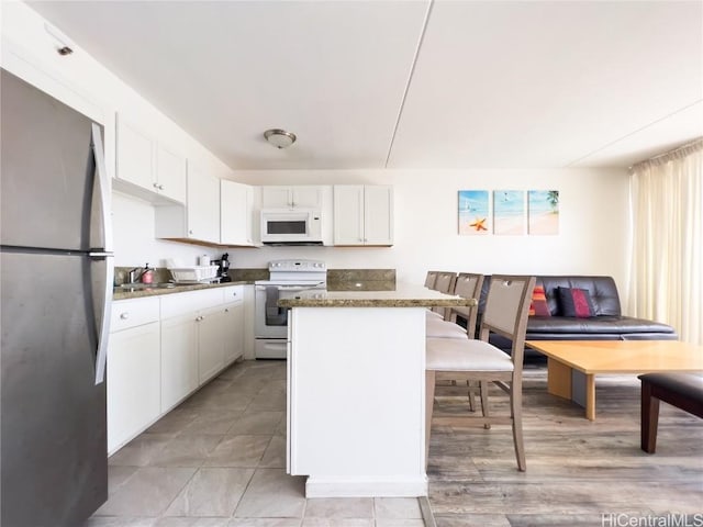 kitchen with white appliances, white cabinets, and a kitchen island