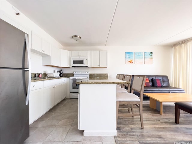 201 Ohua Ave Unit 1803, Honolulu, HI 96815 - kitchen featuring white appliances, white cabinets, a kitchen island, light tile patterned floors, and a sink