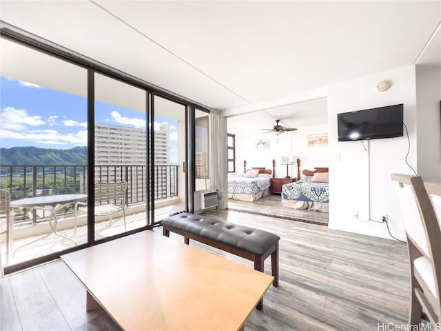 living area featuring expansive windows, ceiling fan, wood finished floors, and a mountain view