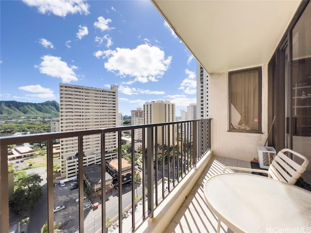 balcony featuring a view of city, cooling unit, and a mountain view