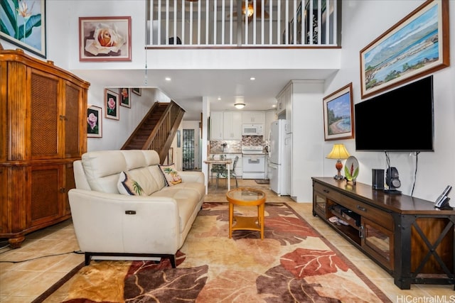 living area featuring light tile patterned flooring, a towering ceiling, and stairs