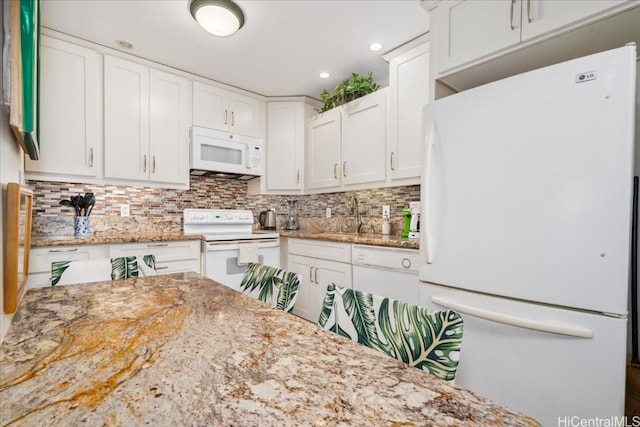 kitchen featuring tasteful backsplash, white cabinets, a sink, light stone countertops, and white appliances