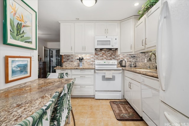 kitchen with decorative backsplash, light tile patterned flooring, a sink, white cabinetry, and white appliances