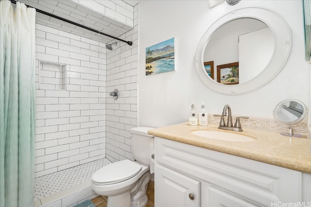 full bath with a tile shower, vanity, and toilet