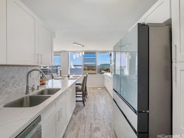 kitchen with stainless steel appliances, backsplash, light wood-style floors, white cabinetry, and a sink