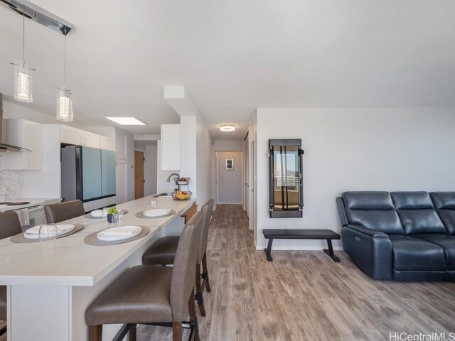 kitchen featuring white cabinets, a kitchen breakfast bar, light countertops, and freestanding refrigerator