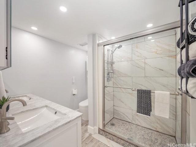 full bath with double vanity, recessed lighting, toilet, a sink, and a shower stall