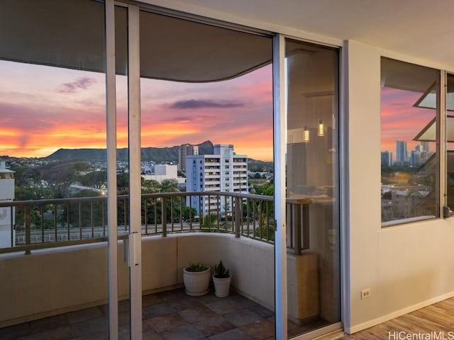 balcony at dusk featuring a mountain view and a city view