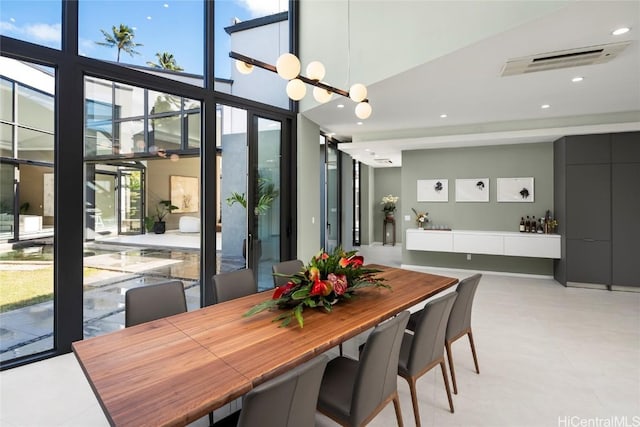 dining room featuring visible vents, a chandelier, a wall of windows, recessed lighting, and a high ceiling