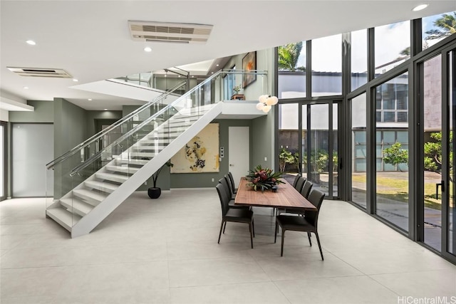 dining area featuring visible vents, stairway, floor to ceiling windows, a towering ceiling, and tile patterned floors