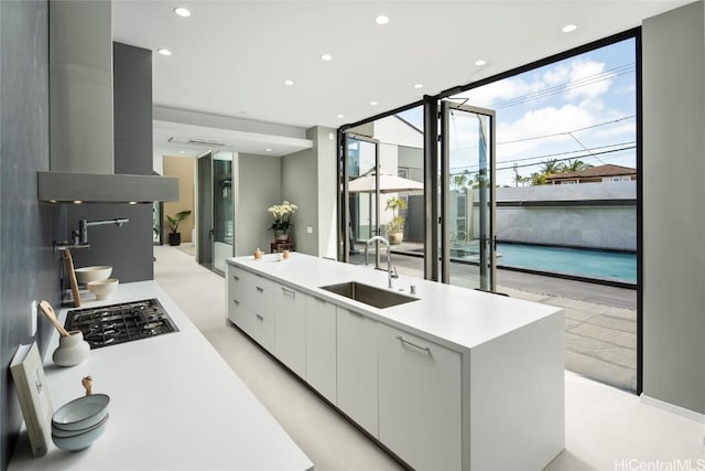 kitchen featuring a sink, floor to ceiling windows, island exhaust hood, white cabinetry, and modern cabinets