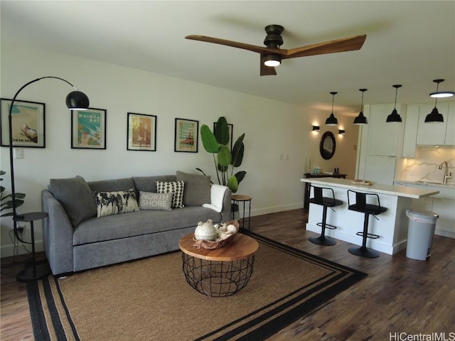 living area featuring dark wood-style floors, baseboards, and a ceiling fan