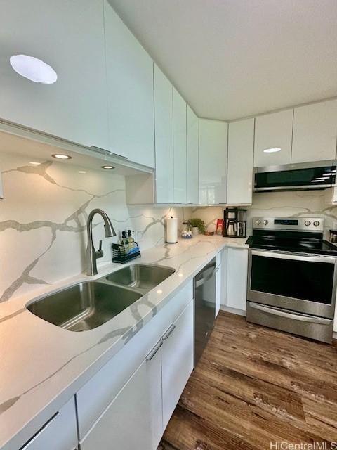 kitchen with white cabinets, appliances with stainless steel finishes, dark wood finished floors, and a sink