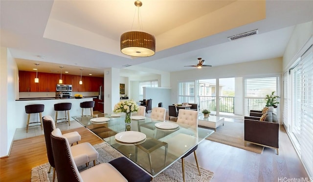 dining area featuring light wood-type flooring, ceiling fan, and visible vents