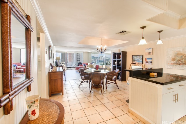 kitchen with a chandelier, open floor plan, hanging light fixtures, dark countertops, and crown molding