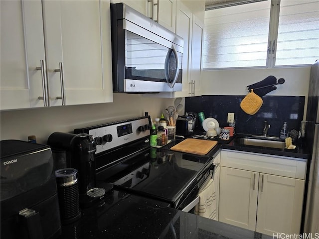 kitchen with white cabinets, backsplash, stainless steel appliances, and a sink