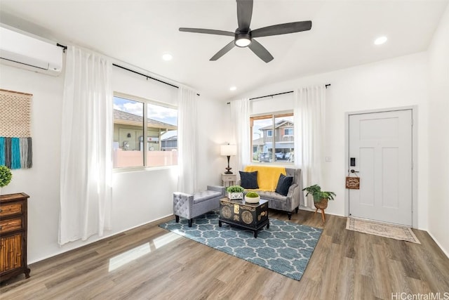 living area with a healthy amount of sunlight, a wall unit AC, and wood finished floors