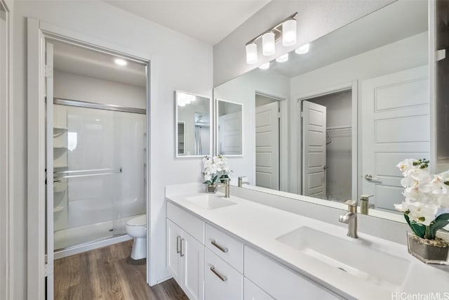 full bathroom with toilet, a stall shower, a sink, and wood finished floors