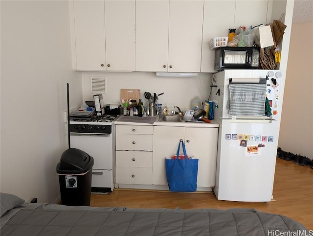 kitchen featuring light wood-type flooring, white appliances, visible vents, and white cabinets