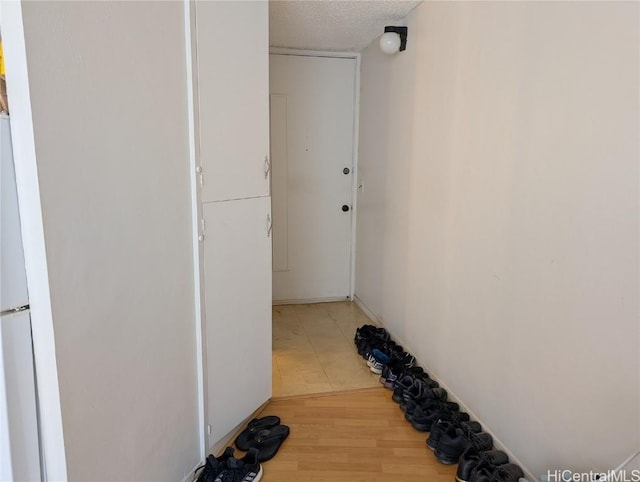 corridor with a textured ceiling and wood finished floors