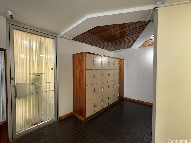 hall featuring brick floor, mail area, and baseboards