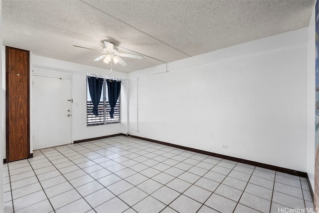 empty room with a textured ceiling, a ceiling fan, and baseboards