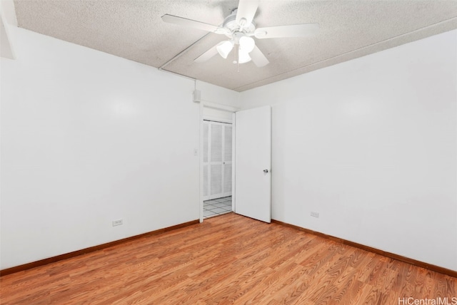 unfurnished room with a textured ceiling, ceiling fan, light wood finished floors, and baseboards