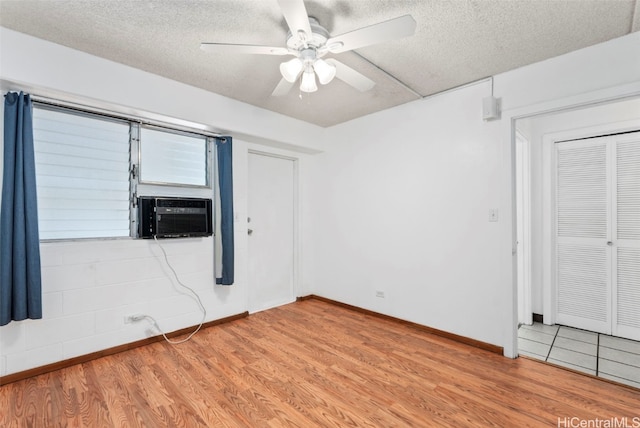 unfurnished bedroom featuring a closet, light wood-style floors, a ceiling fan, a textured ceiling, and cooling unit