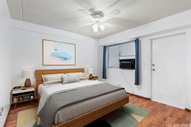 bedroom featuring a textured ceiling, ceiling fan, cooling unit, and wood finished floors