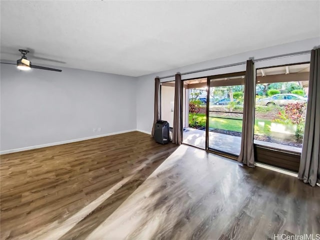 empty room featuring ceiling fan, baseboards, and wood finished floors