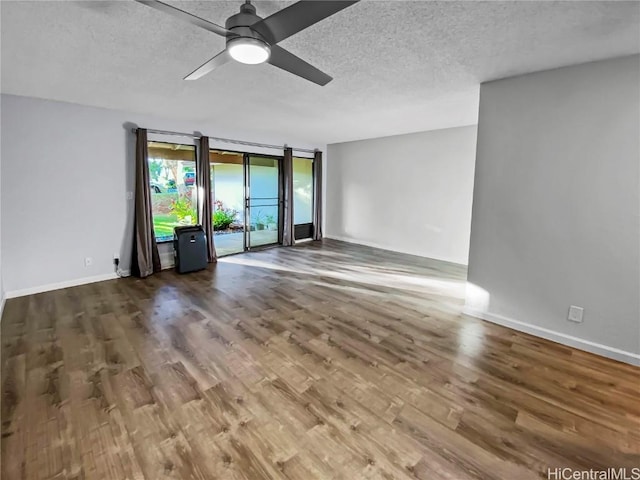 spare room with ceiling fan, a textured ceiling, baseboards, and wood finished floors