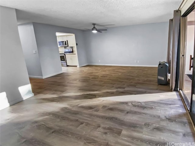 spare room with a textured ceiling, ceiling fan, dark wood-style flooring, and baseboards