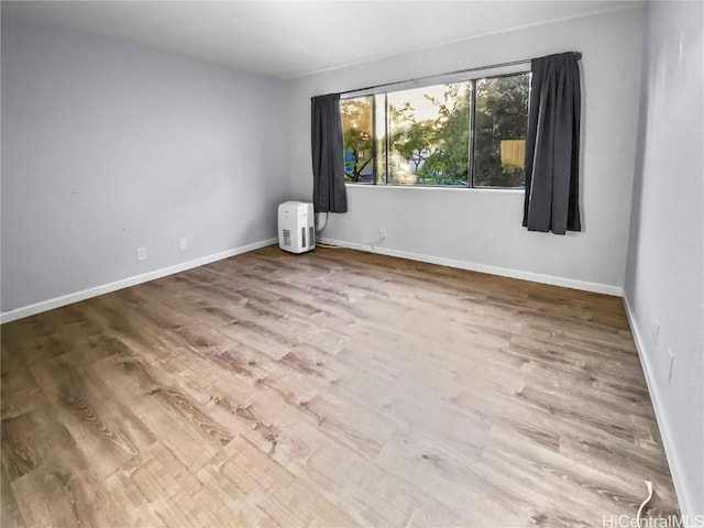 spare room featuring baseboards and wood finished floors