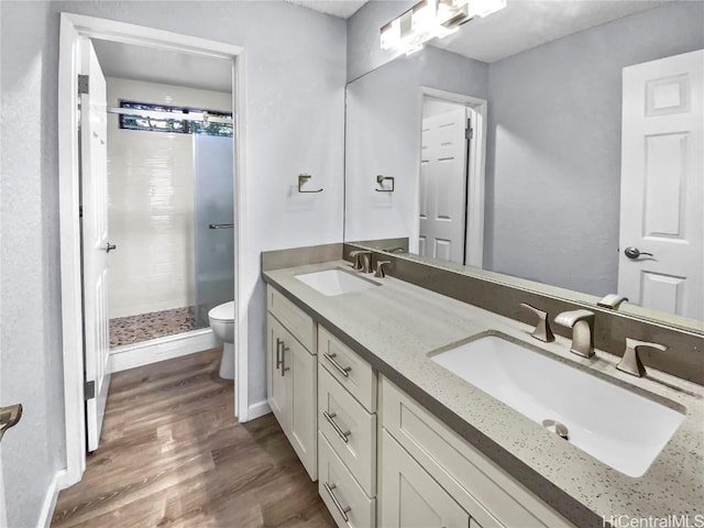 bathroom with wood finished floors, a sink, toilet, and a shower stall