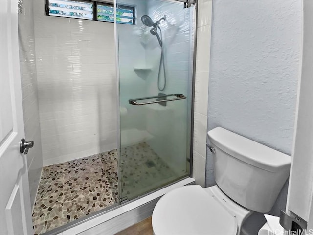 bathroom featuring a stall shower, a textured wall, and toilet